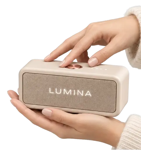 To hænder holder en beige Lumina Bloom højttaler